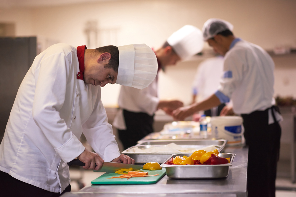 chef in hotel kitchen  slice  vegetables with knife and prepare food